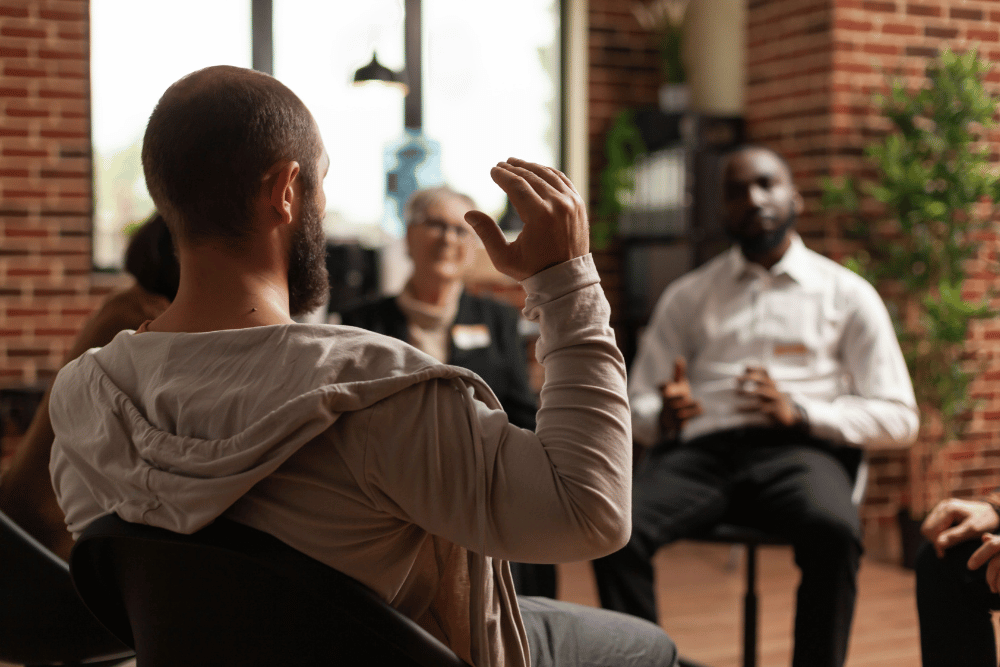 Man sharing his addiction story with friends and mentors during group therapy