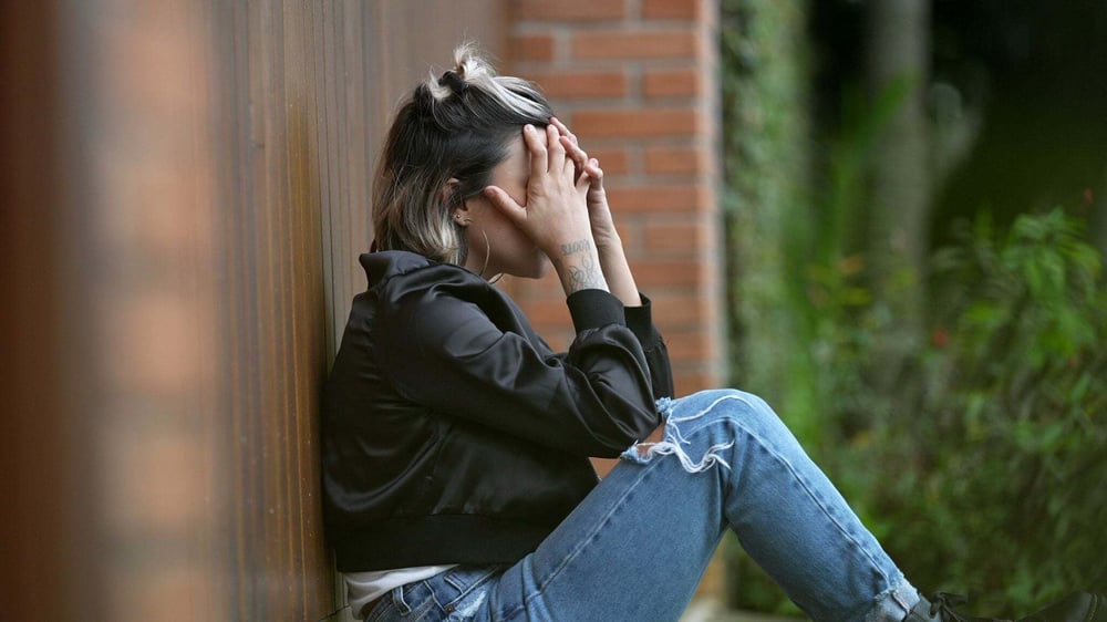 A woman at rock bottom from alcohol abuse covers her face in regret.