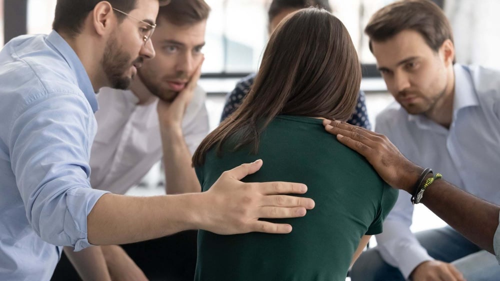 A support group comforts a woman seeking help after reaching rock bottom in alcohol addiction