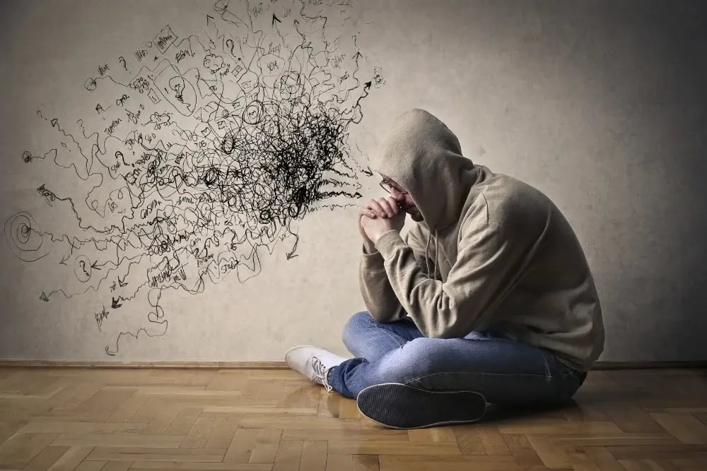 A man on the floor, chaotic scribbles near his head signaling the psychological symptoms of feening.