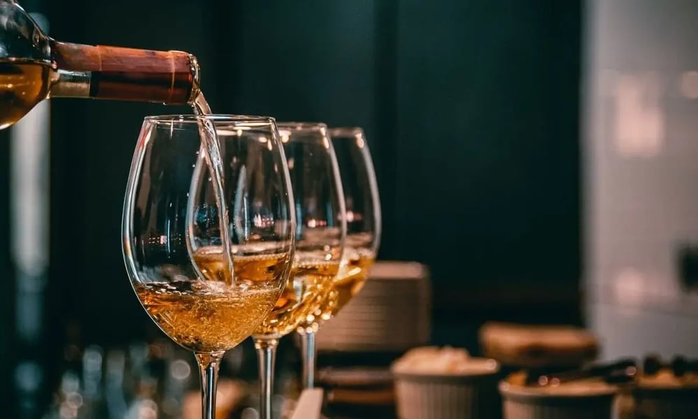 Alcohol being poured into glasses, representing alcohol use which may require treatment with alcoholism medication.