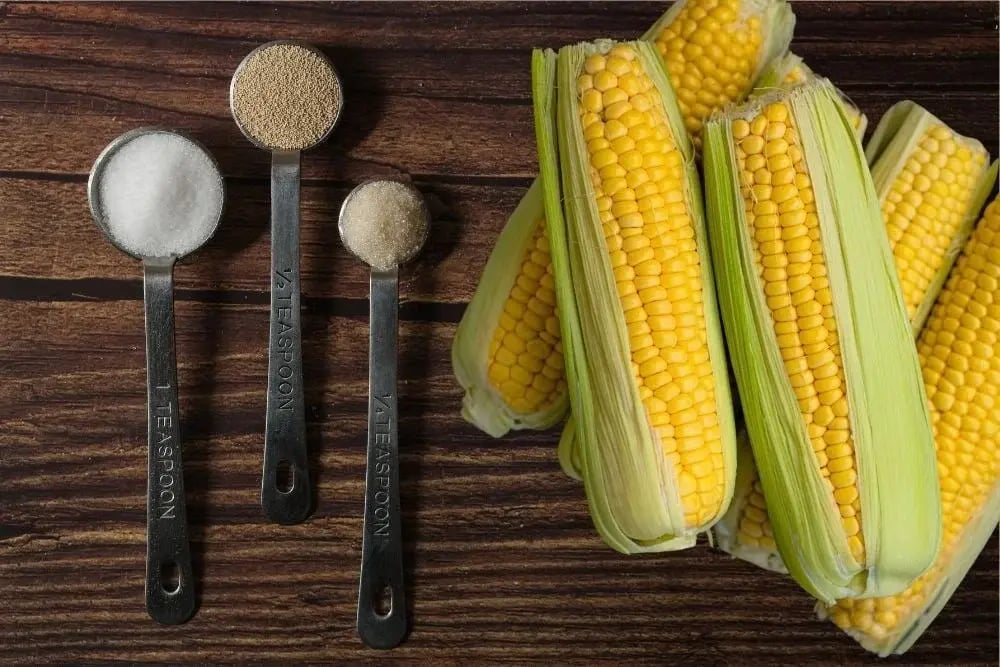Corn with sugar and yeast on a wooden table illustrating what is in moonshine liquor