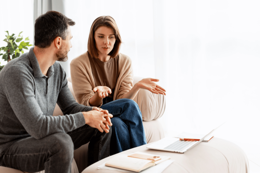 Couple on the couch discussing and noting the pros and cons of inpatient vs. outpatient rehab