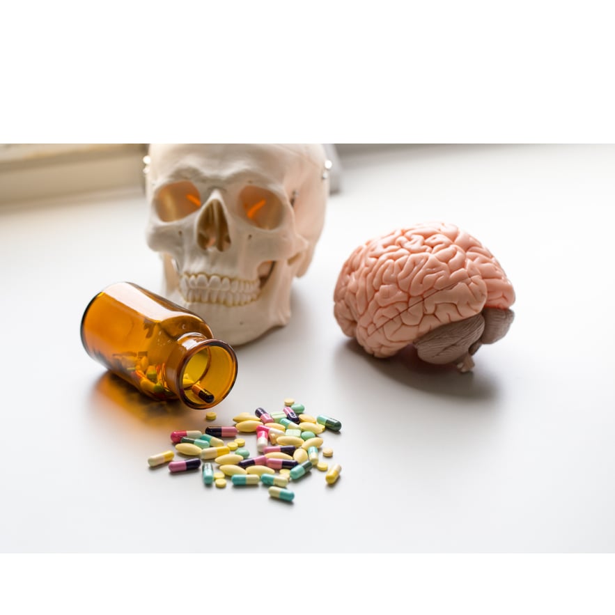 Spilled pills, amber bottle, skull model, and brain model symbolizing Benzo Fury’s effects on the brain