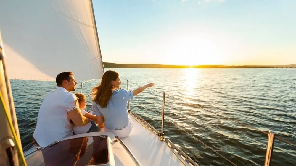 Family relaxing on a sailboat at sunset