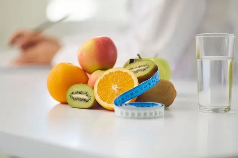 Oranges, apples, kiwis, water, and a measuring tape symbolize the importance of health in holistic treatment
