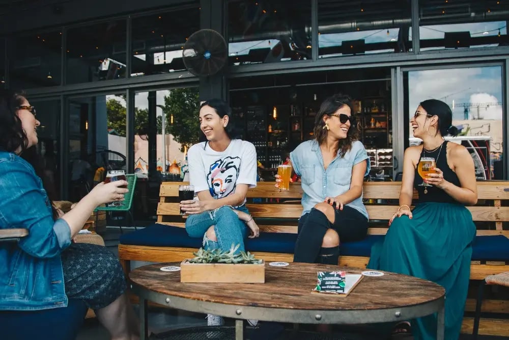 Girls drinking at a bar. Avoiding triggers such as a drinking bar can reduce alcohol cravings