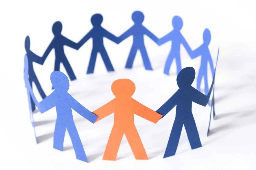  A circle of cardboard cutouts holding hands represents the supportive energy of group therapy for addiction.