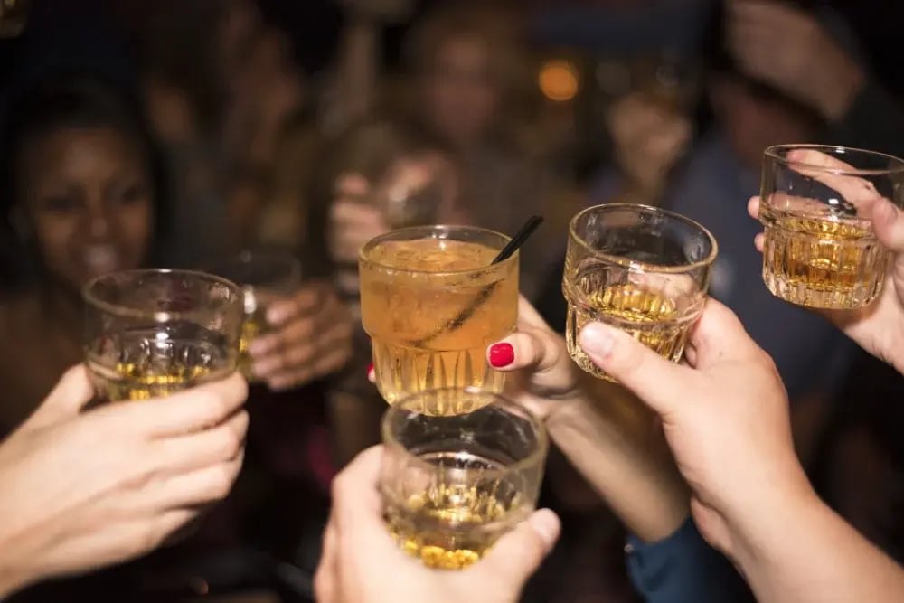 A few people toasting with glasses of alcohol. Adopt safe drinking practices to prevent alcohol dehydration.