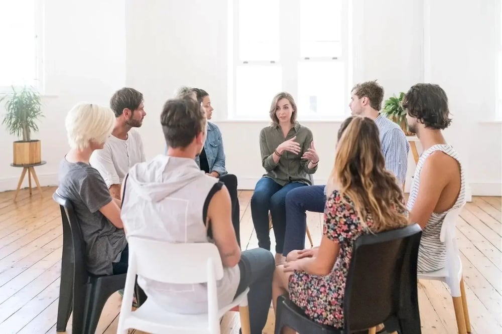 People participating in a group therapy session at a rehab center discussing addiction recovery.