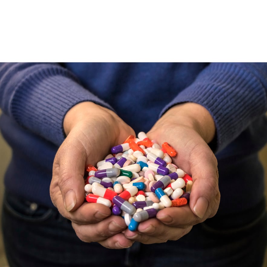 A person with both hands full of pills, symbolizing a trazodone overdose.