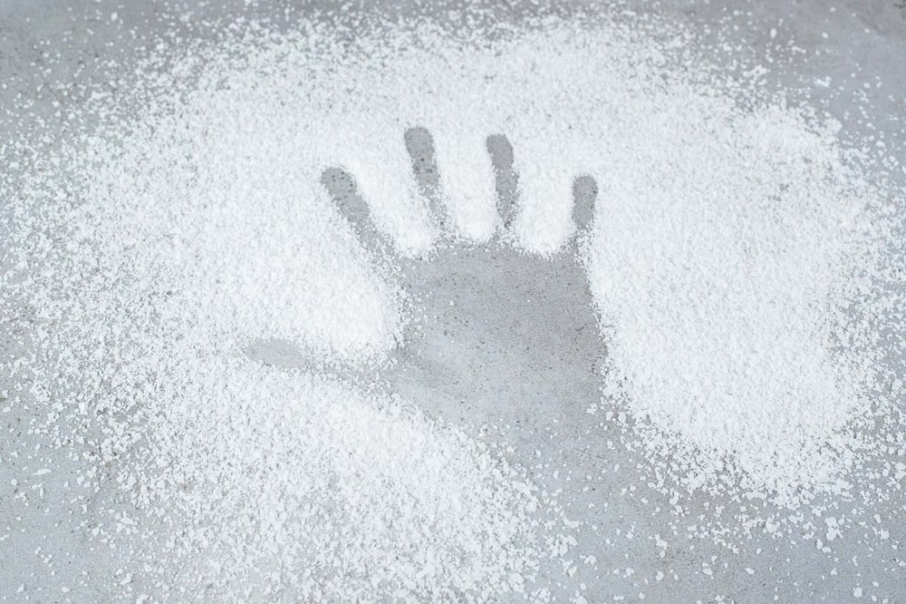 Handprint pressed into a pile of powder symbolizing the dangers of purple heroin and opioid abuse.