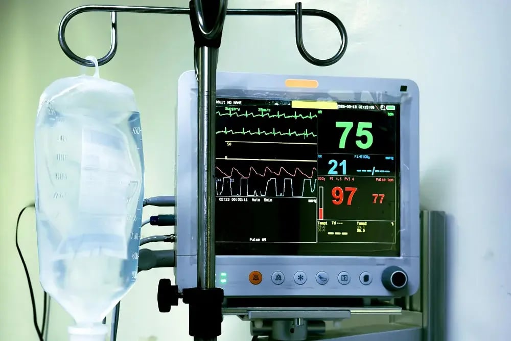 An IV vial and vital signs monitor, signifying the urgent care needed after drinking rubbing alcohol.