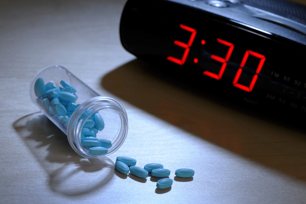 A clock showing 3:30 AM next to sleeping pills, which insomniacs may become addicted to.