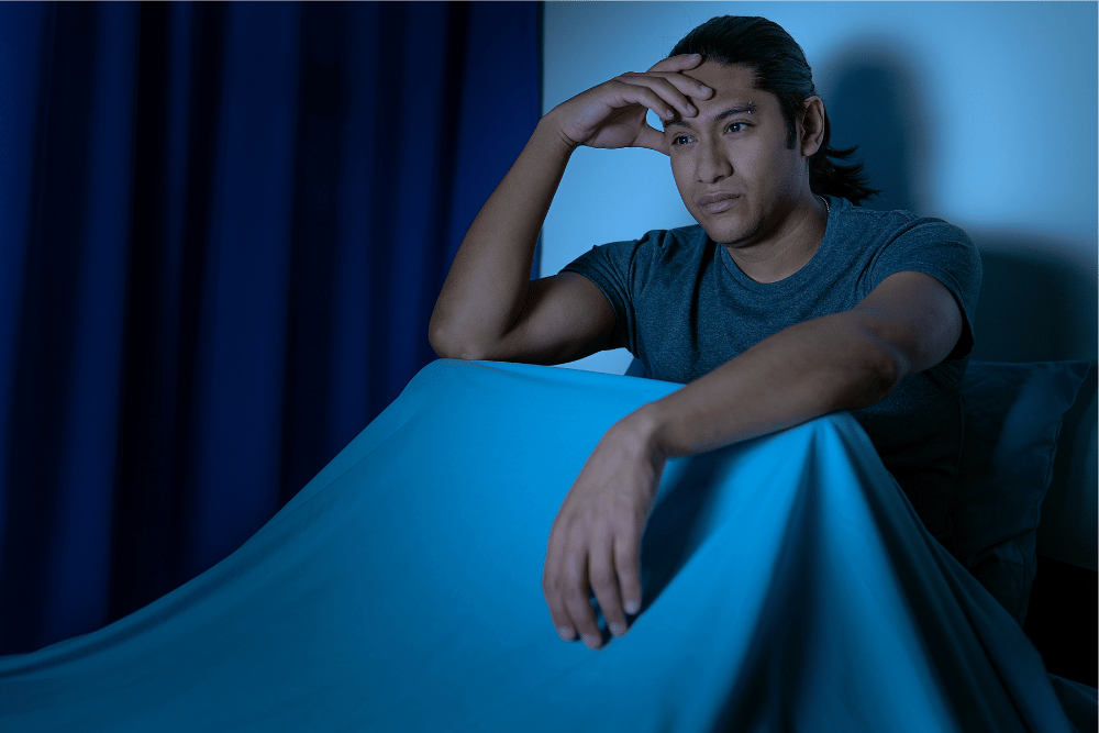 Man with insomnia sitting in bed. Gabapentin and Xanax are both used to treat sleep disorders.