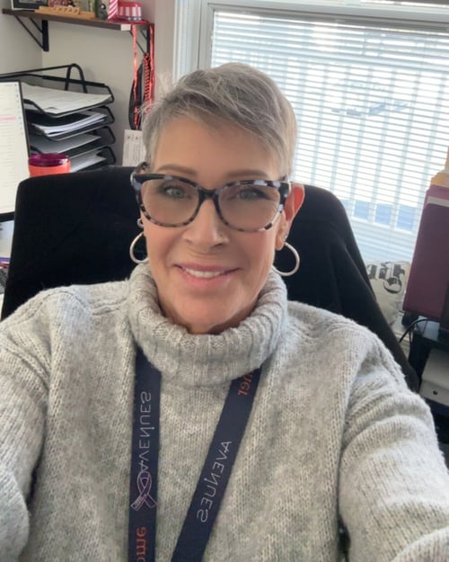 Image of woman in glasses and lanyard as Avenues shares Kathi's story