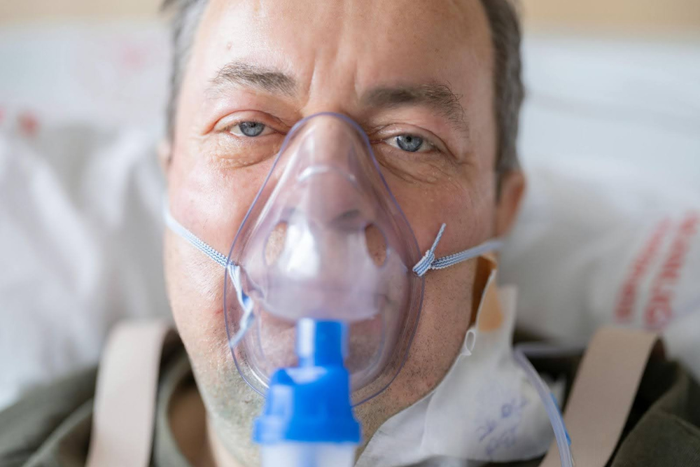 Man with an oxygen mask experiencing labored breathing from combining gabapentin and alcohol. 