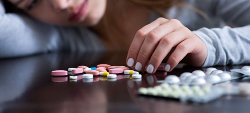 Image of girl overdosing near piles of pills as Avenues Recovery shares signs of codeine overdose