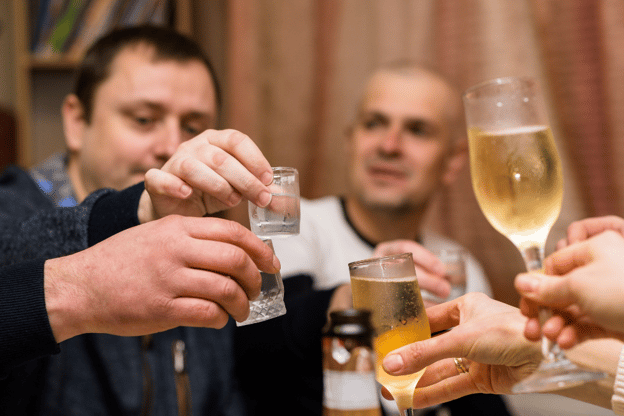 Friends drinking together, but one person looks slightly worried about the drinking habits of his friend.