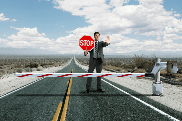 A man holding a stop sign on a deserted road, symbolizing setting firm boundaries with addiction.