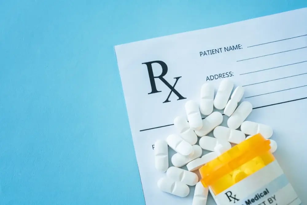 Pills scattered on a prescription. Medications such as Disulfiram and Naltrexone help curb alcohol cravings.