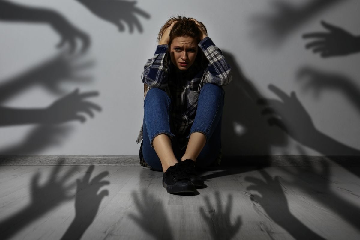 Image of girl huddled against wall escaping shadows as Avenues Recovery explores schizophrenia and drug use