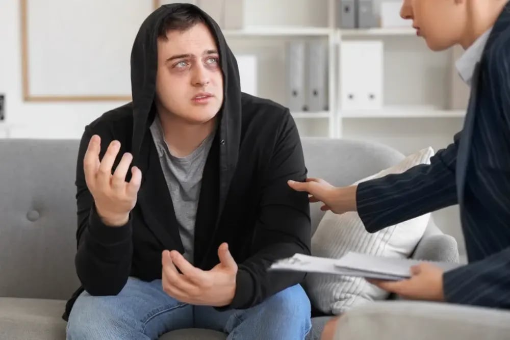 A professional patting a college student’s arm, helping him in his struggle with substance abuse.