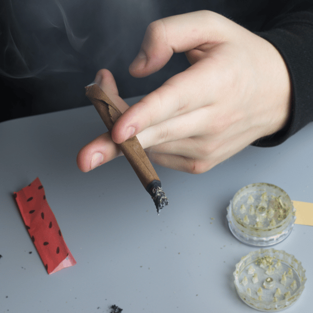 Young person smoking marijuana, with additional paraphernalia nearby, unaware of the effects of cannabis long term.&nbsp;