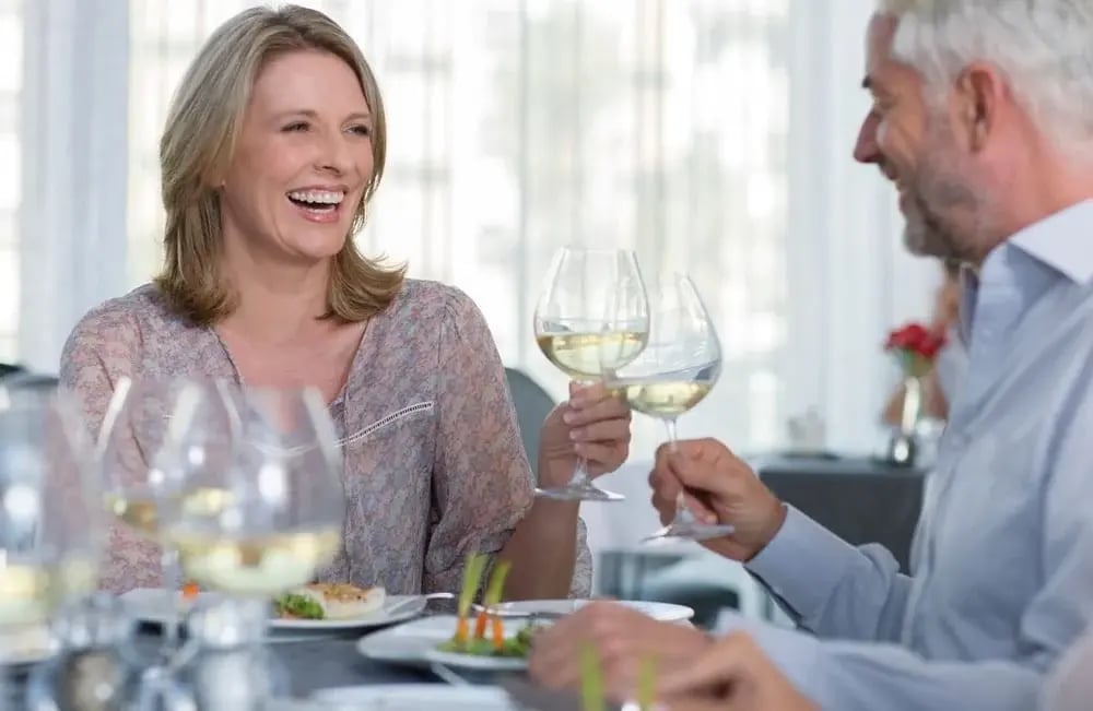 A man and woman toasting on glasses of white wine. Avenues provides guidance on responsible drinking.