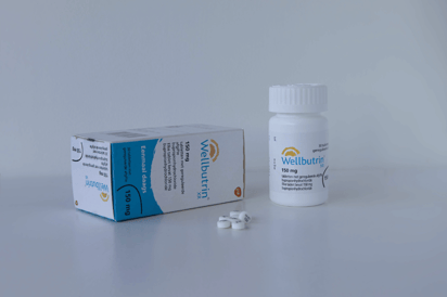 Wellbutrin pills beside the pill box and bottle.