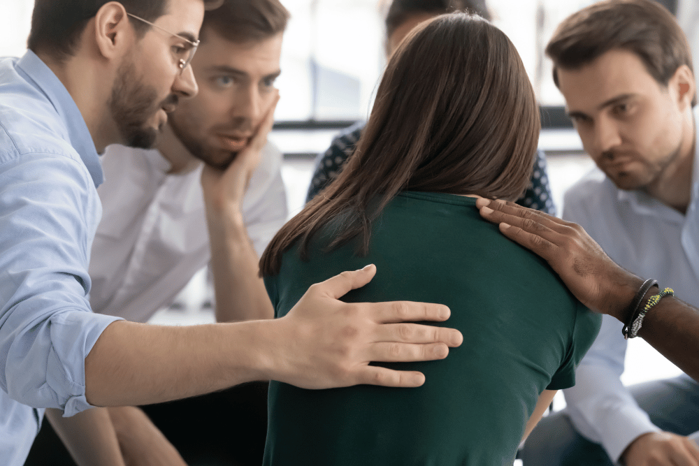 Woman getting support from family members and friends for her alcoholic spouse in an intervention meeting