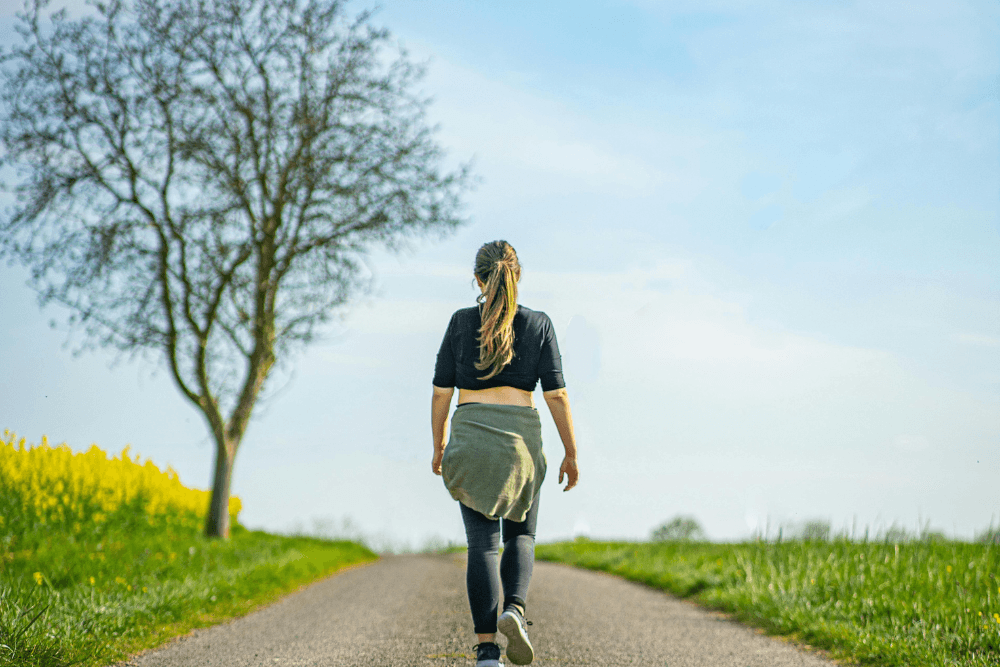 A woman walking on a path. Taking a walk can distract you from a craving.