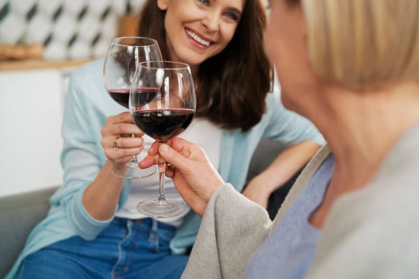 Image of two women smiling with glasses of wine as Avenues Recovery explores where to find the best non-alcoholic drinks and sober bars in Maryland