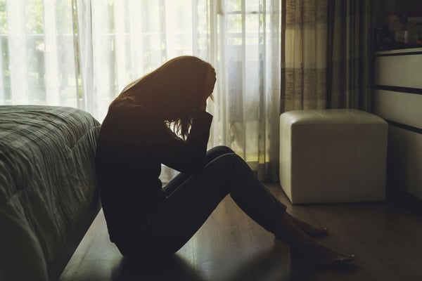 Image of depressed woman with head in hands as Avenues Recovery explores where to find the best non-alcoholic drinks and sober bars in Maryland