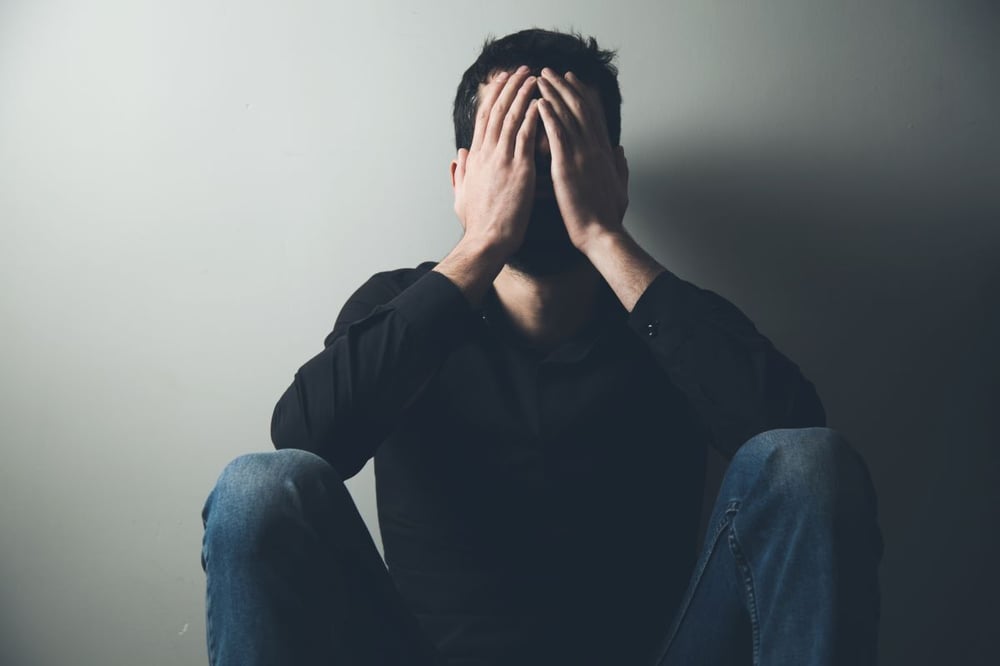 Image of depressed man with head in hands as Avenues Recovery explores "is codeine addictive"?