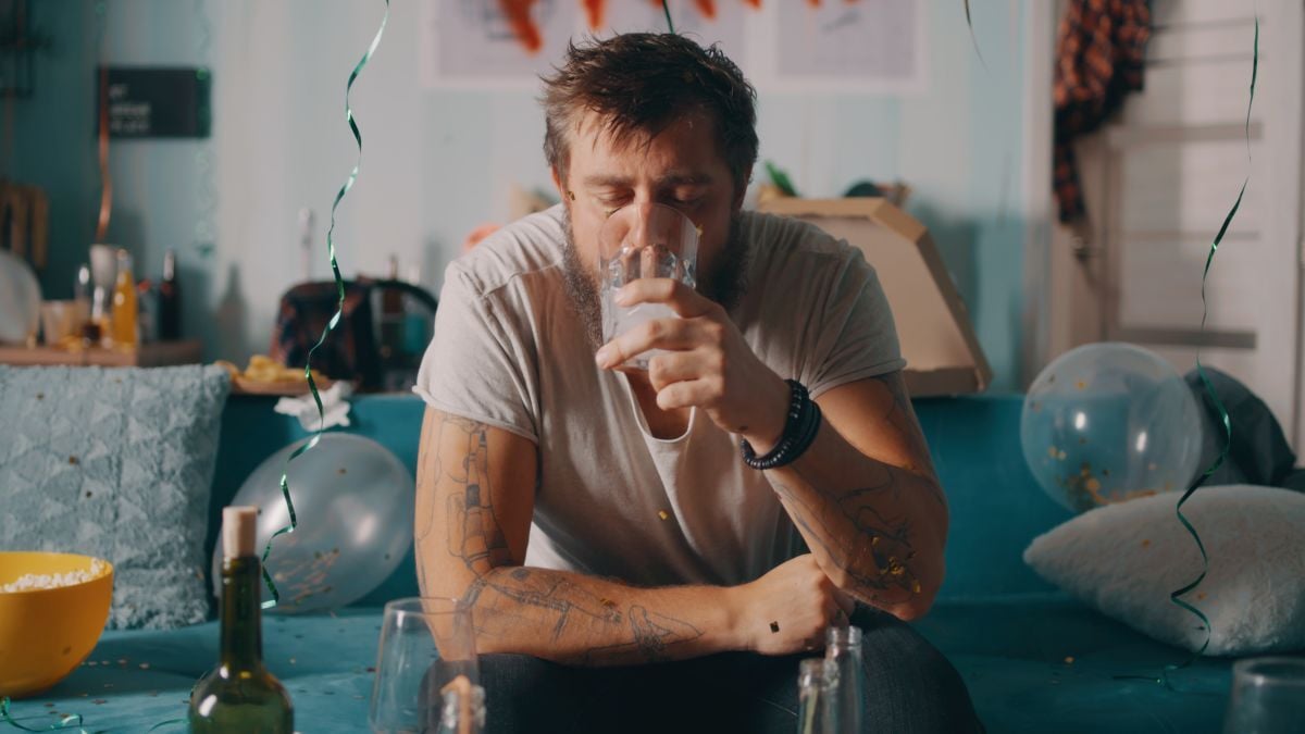 Image of man drinking water at party as Avenues Recovery explores alcohol dehydration
