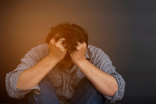 Image of distressed man holding head in hands as Avenues Recovery explores "Is Modafinil addictive"?