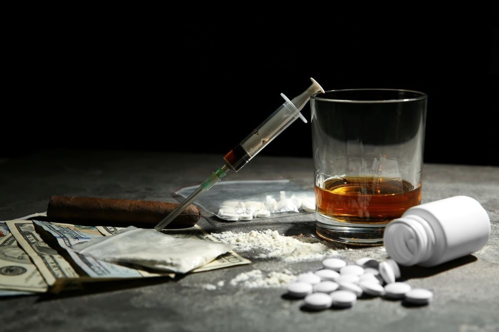 Image of drugs, alcohol, and money as Avenues Recovery explores heroin and alcohol