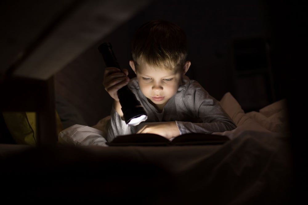 Image of child reading in bed as Avenues explains why does alcohol make me sleepy