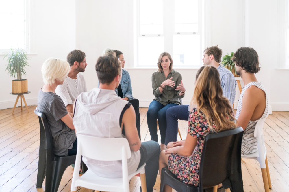 Adults sitting in a support group circle, sharing experiences with weed and Vyvanse addiction. Avenues Recovery