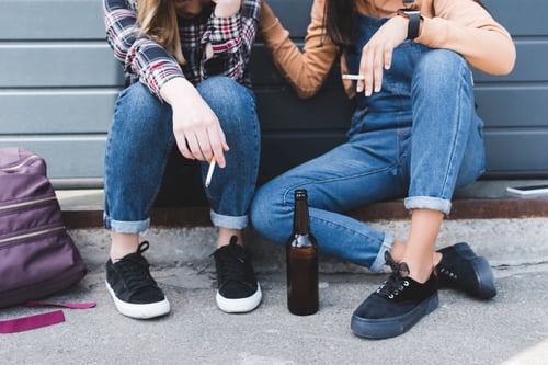 Image of teens smoking and drinking on stoop as Avenues Recovery shares helpful Pennsylvania Crisis Helpline numbers